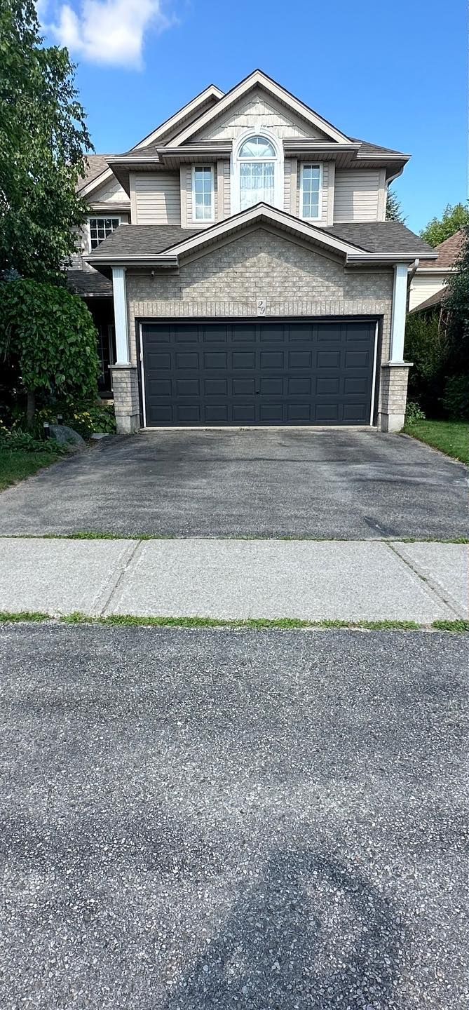 A large house with a black garage door and a driveway.