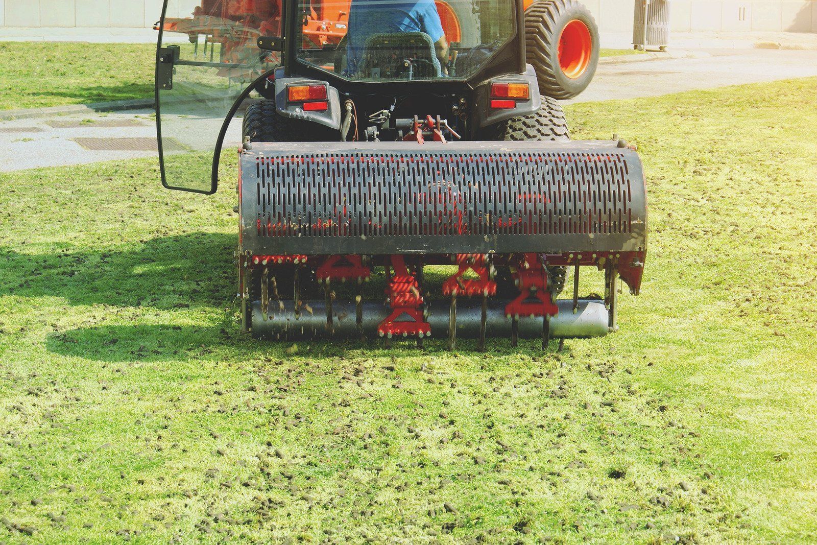 A tractor is spreading fertilizer on a lush green lawn.