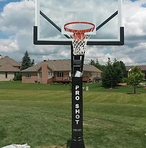 A basketball hoop is sitting in the middle of a grassy field.