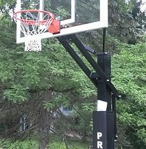 A basketball hoop is surrounded by trees in a park.