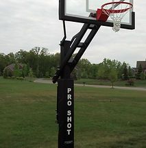 A basketball hoop is sitting in the middle of a grassy field.