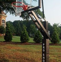 A basketball hoop is sitting in the middle of a grassy field.