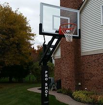 A basketball hoop is attached to the side of a brick house.