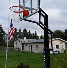 A basketball hoop with an american flag in front of a house.