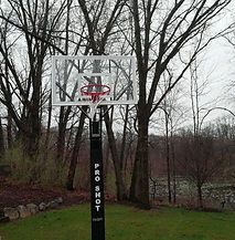 A basketball hoop in a backyard with trees in the background.