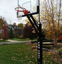 A basketball hoop is sitting in the middle of a lush green park.