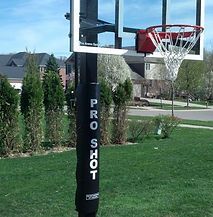 A basketball hoop is sitting on top of a lush green field.