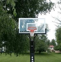 A basketball hoop in a park with trees in the background.