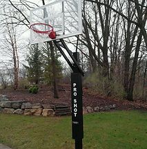 A basketball hoop is sitting in the middle of a lush green field.