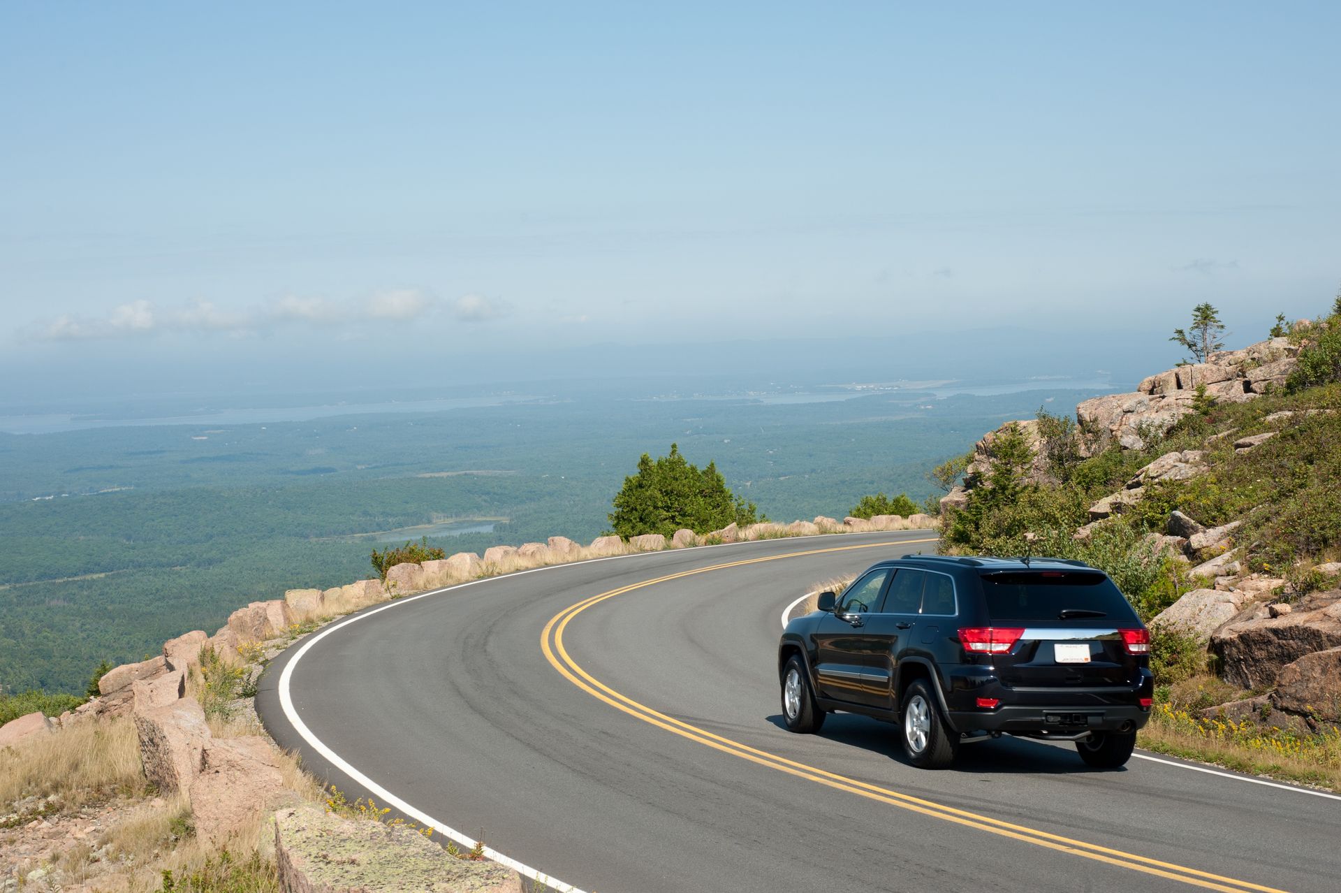 A black suv is driving down a curvy mountain road.