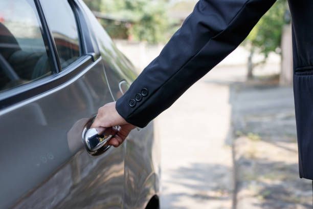 A man in a suit is opening the door of a car.