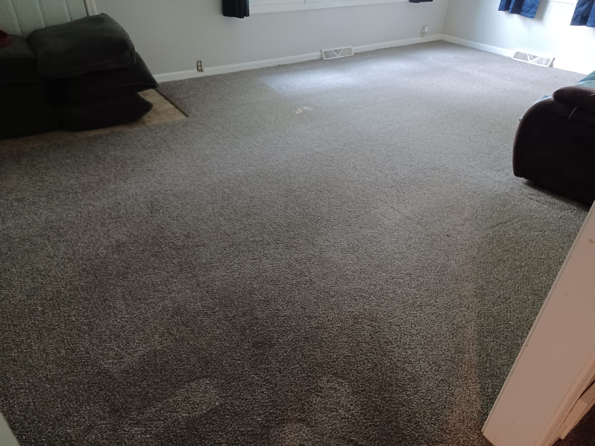 Gray carpeted living room with dark gray couch and a black chair.