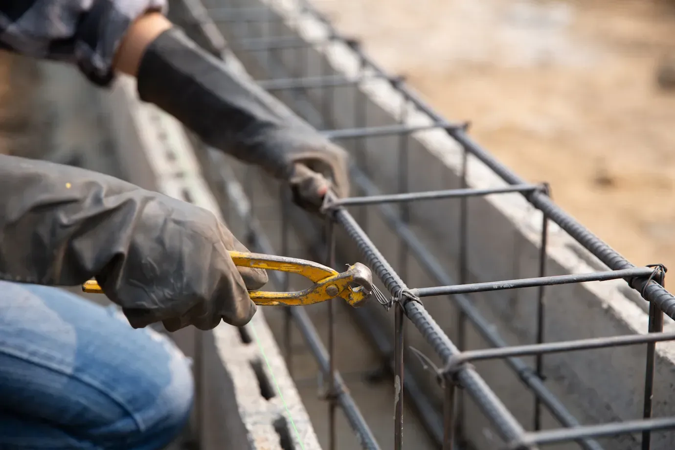 Um trabalhador da construção civil está trabalhando em uma parede de concreto com um alicate.
