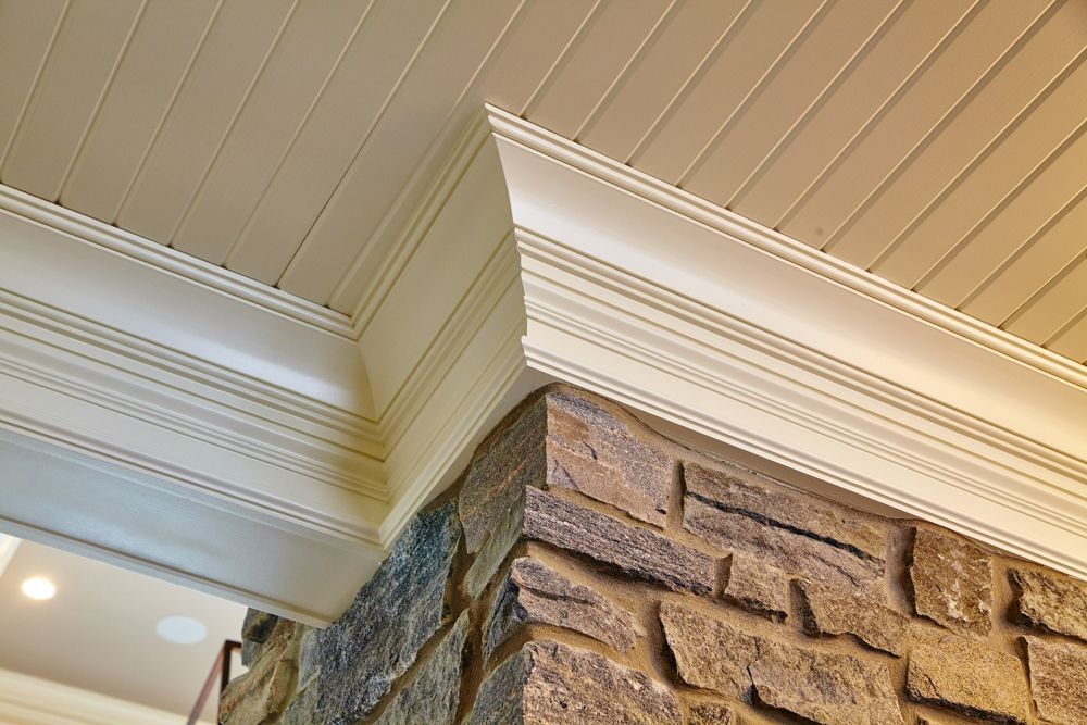 A corner of a room with a brick wall and a ceiling with molding.