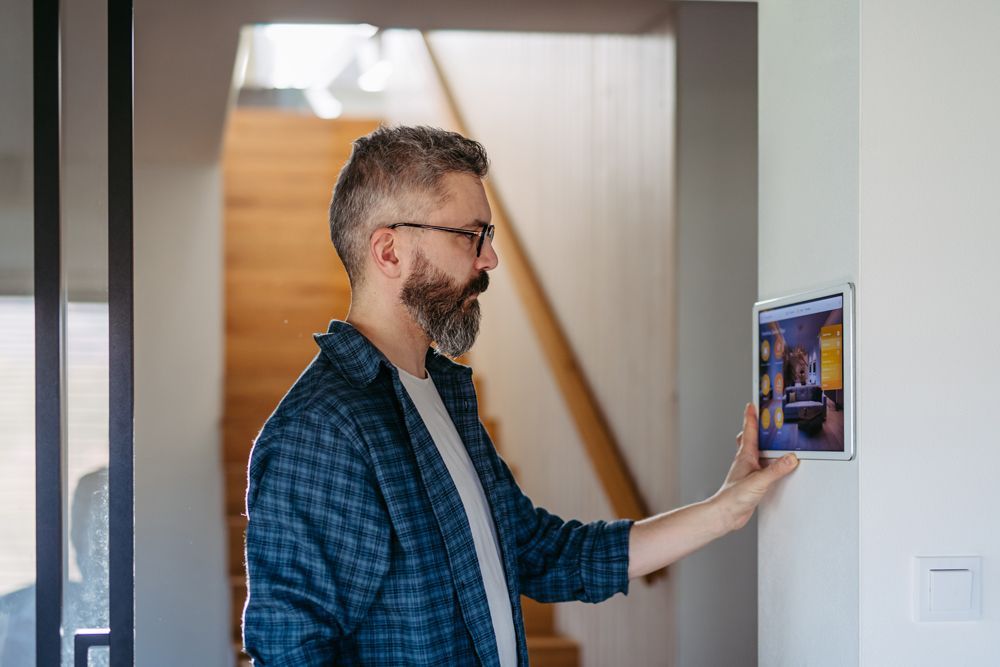 A man is using a tablet to control a smart home.