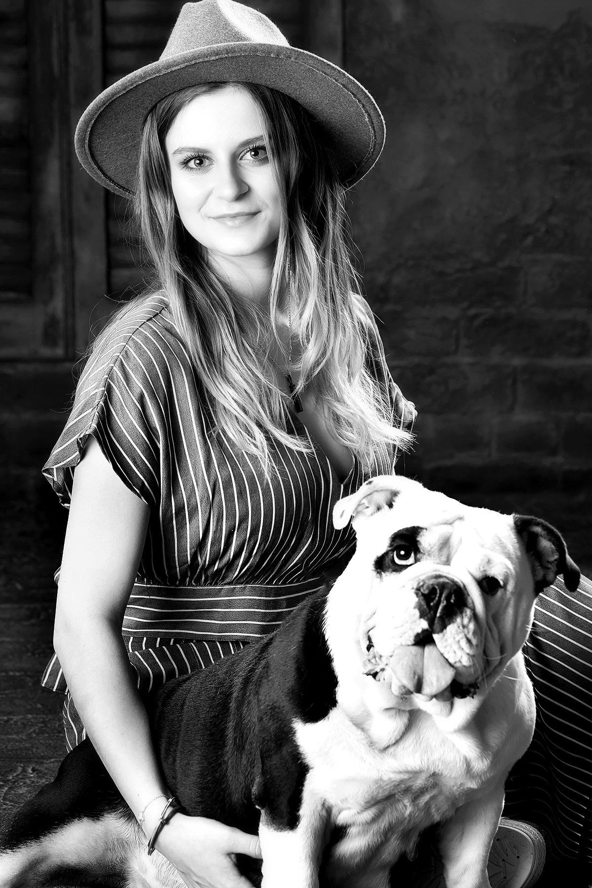A black and white photo of a woman holding a bulldog