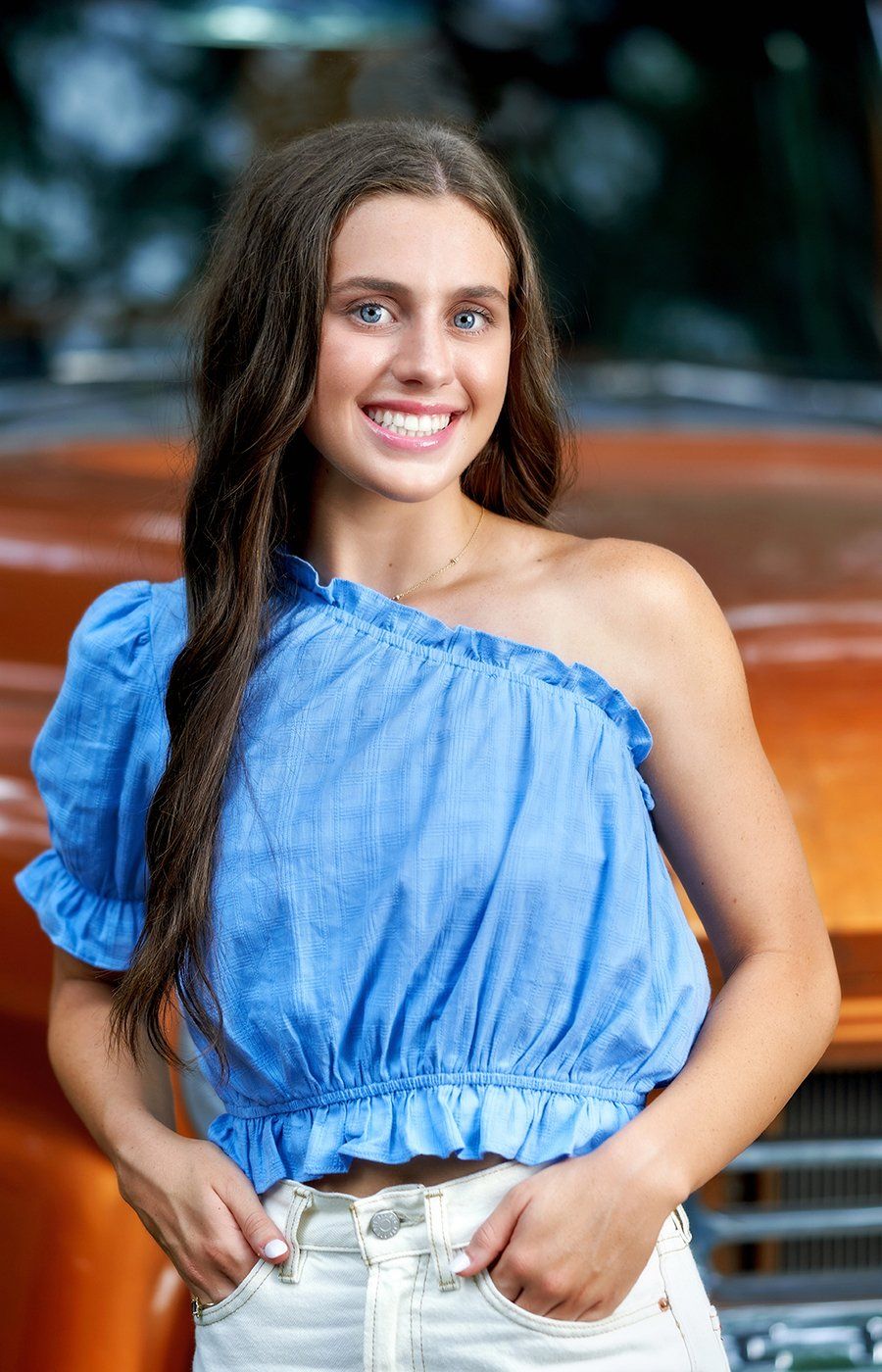 The woman is wearing a blue one shoulder top and white shorts.