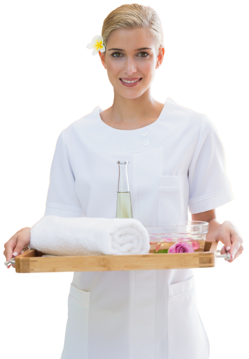 A woman is holding a wooden tray with towels and flowers on it.