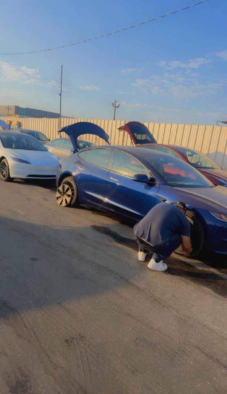 Person checks tire on a blue Tesla.