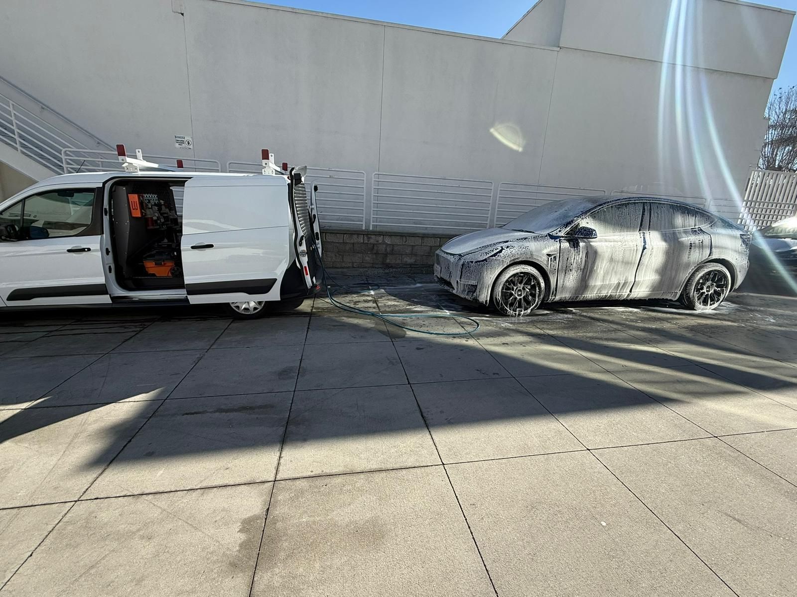 White van and car covered in soap, parked next to each other on a sunny day.