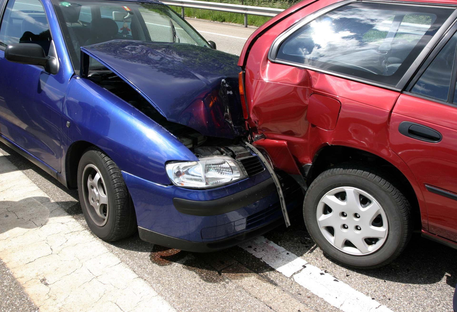 Two cars, blue and red, involved in a collision; visible damage to the front of blue car and side of red car.