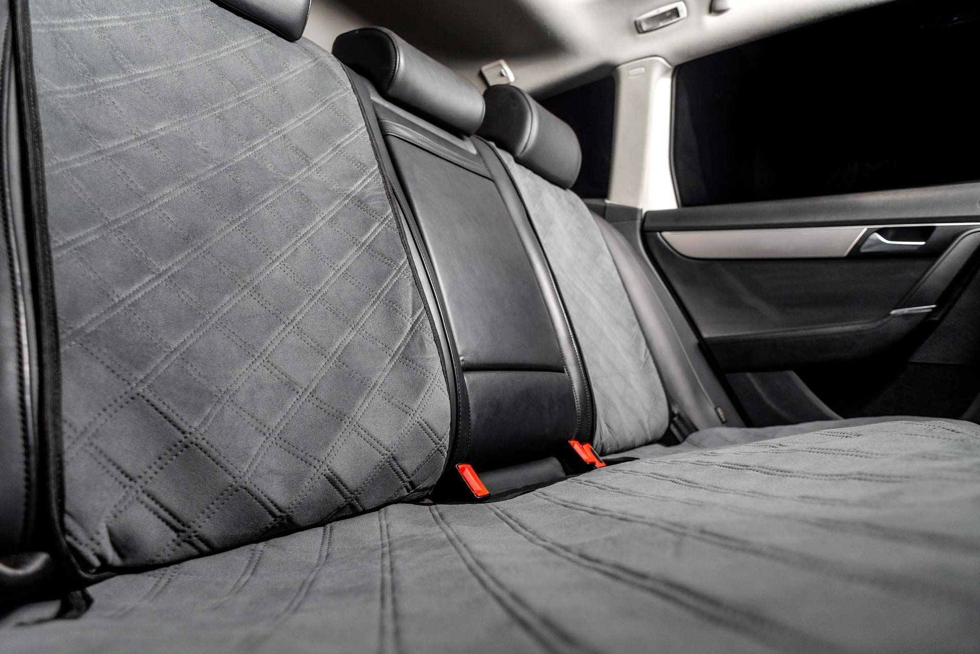 Car back seat covered with gray quilted fabric for protection.