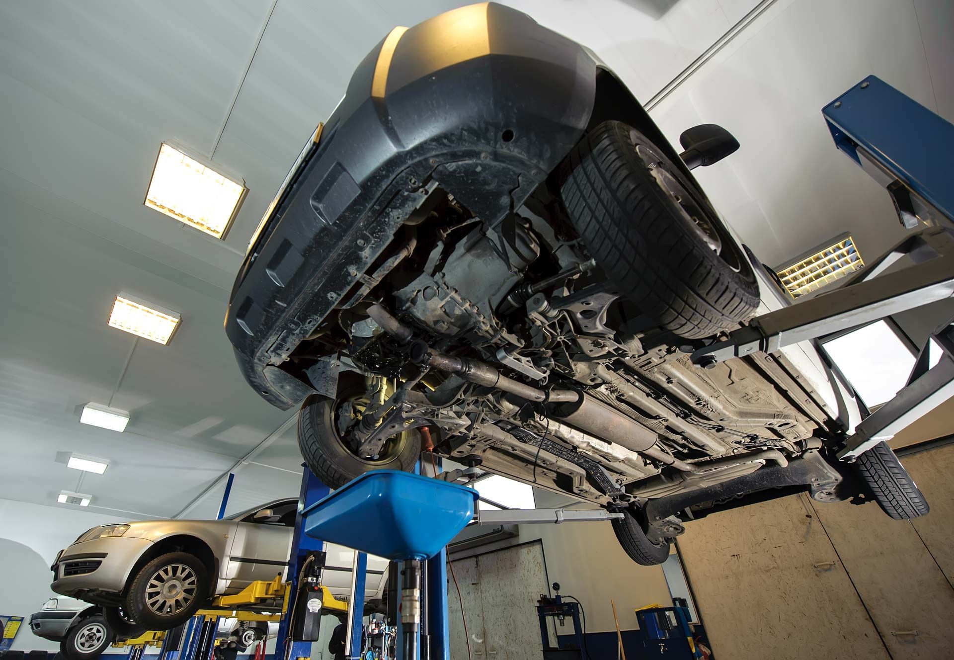 Car raised on a lift in a repair shop, showing undercarriage.