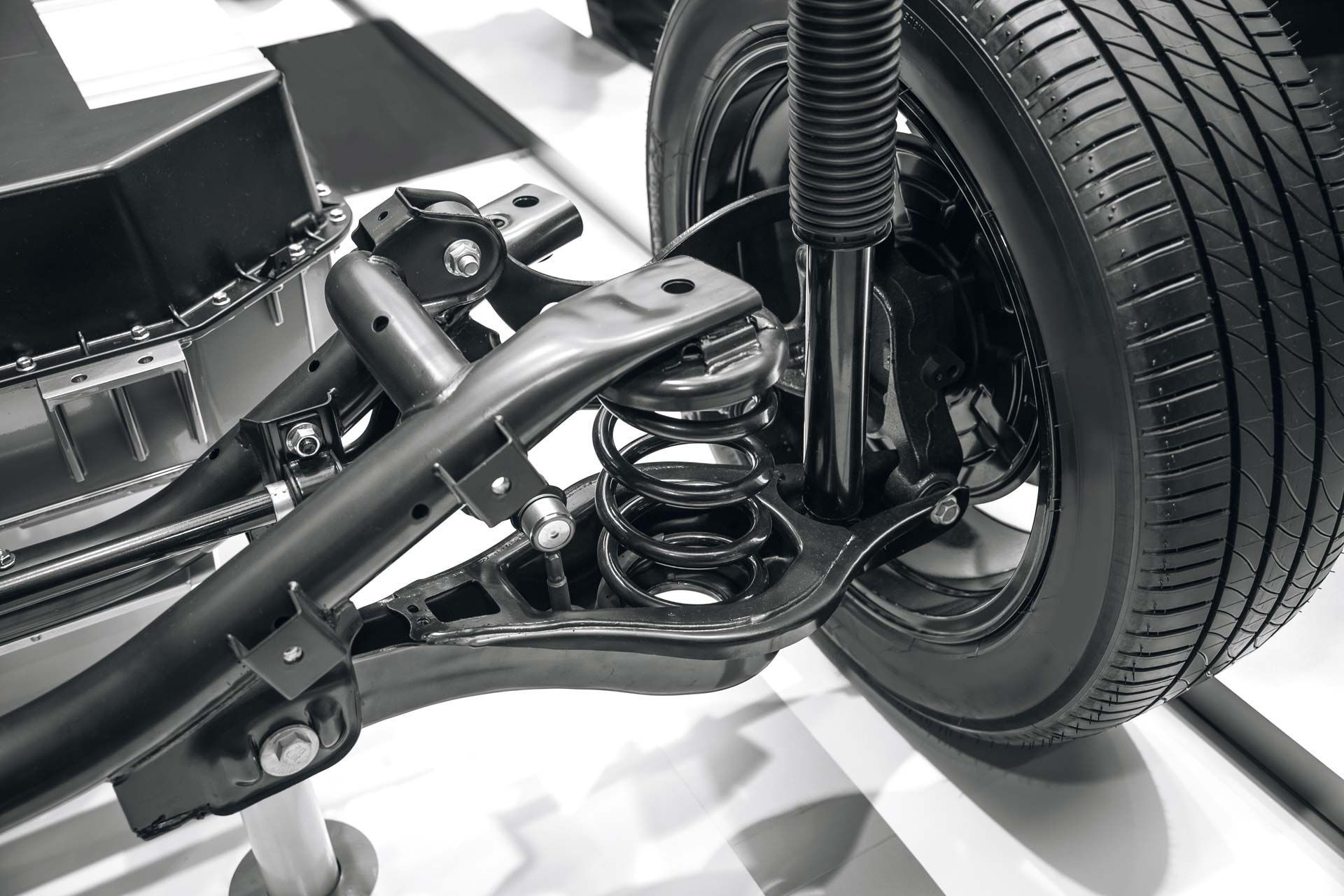 Black car suspension system with tire, spring, and shock absorber.