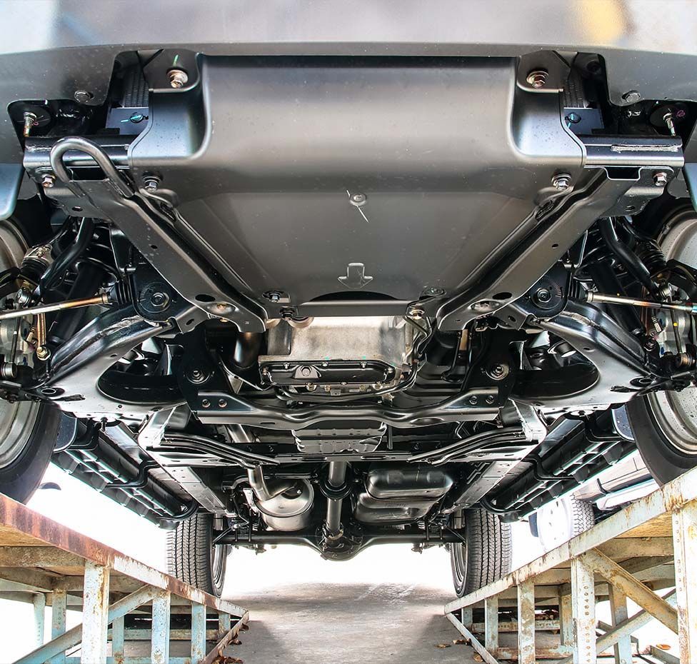 Underside of a car on a lift; shows suspension, exhaust system, and protective panels in a clean, organized arrangement.