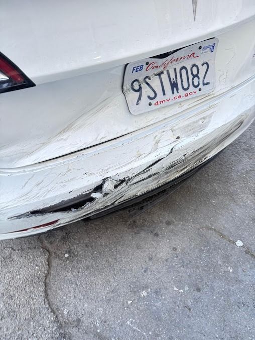 White Tesla car's rear bumper damaged and dented with a California license plate