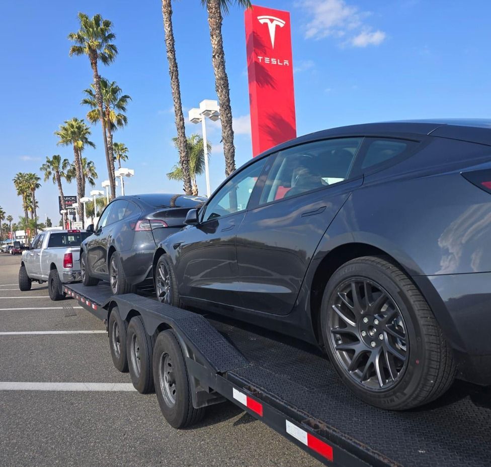 Tesla cars on a trailer at a Tesla dealership.