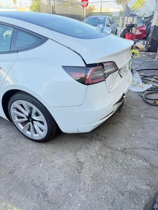 White Tesla car with rear damage.