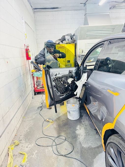 A person repairs a car door in a body shop.