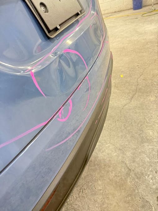 Blue car bumper with dents marked in pink.