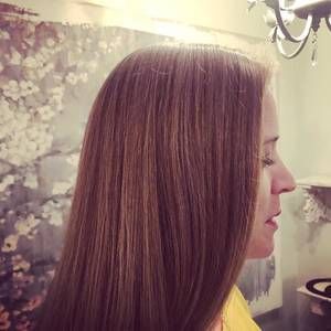 Woman with long brown hair, side profile. Standing in front of floral wall art