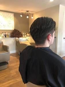 Person with dark hair in a salon chair, back to the camera, after a haircut
