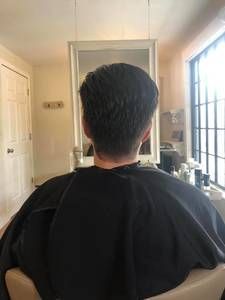 Person in a black cape facing a mirror