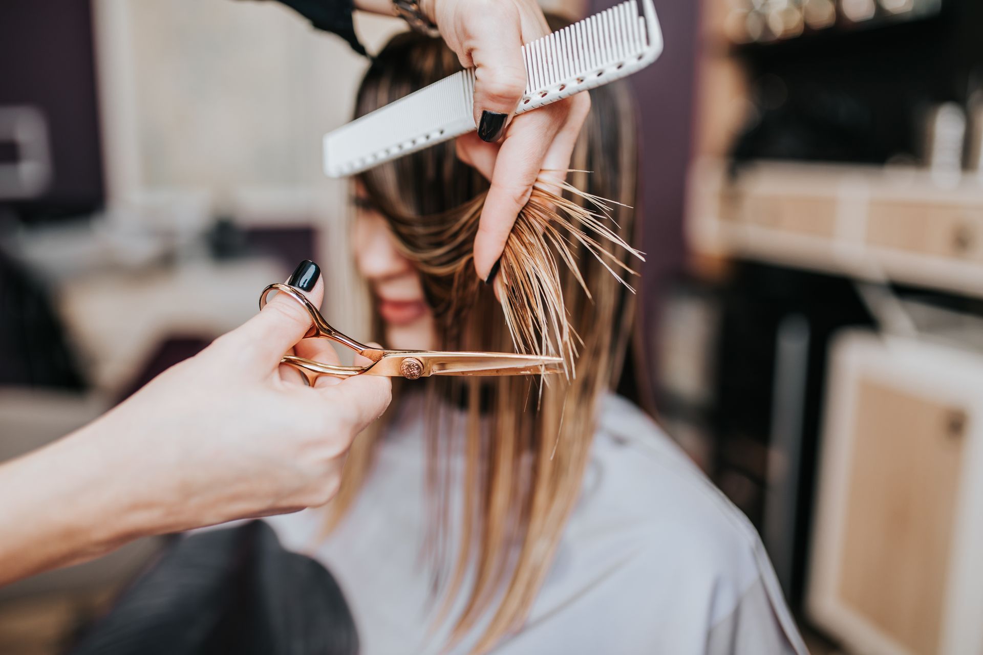 Hairdresser cutting hair with scissors and comb in a salon setting