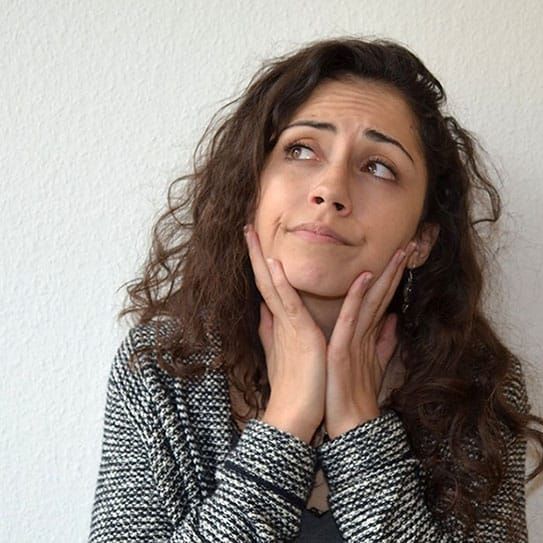 A woman with her hands on her face looking up