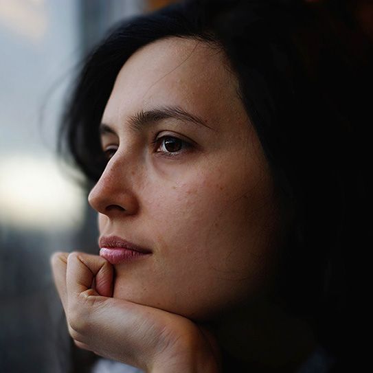 A close up of a woman 's face with her hand on her chin