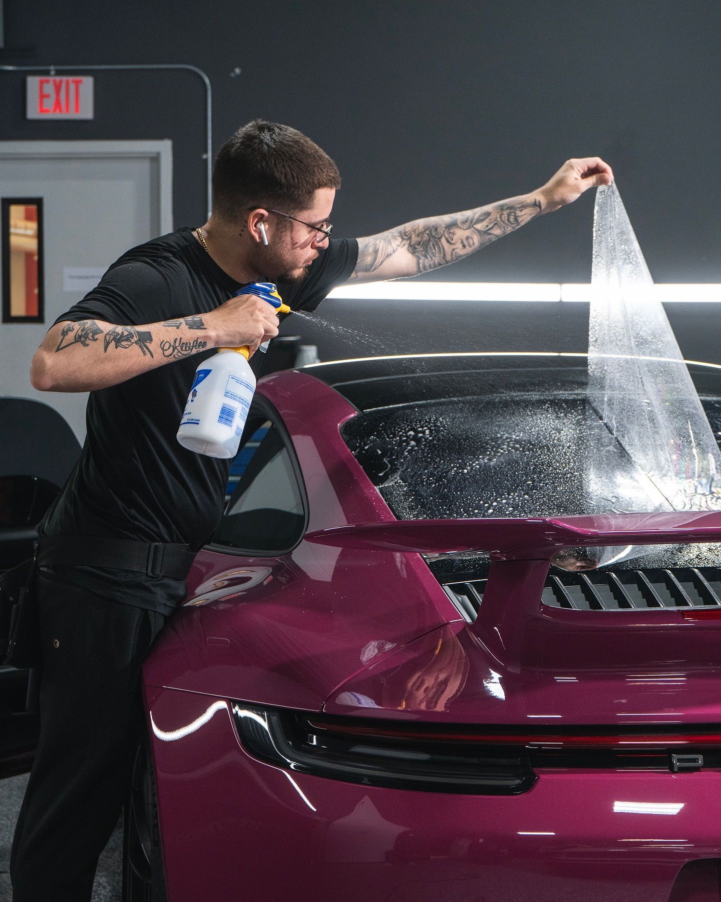 Professional technician precisely applying window tint film to a car door in Naples, FL