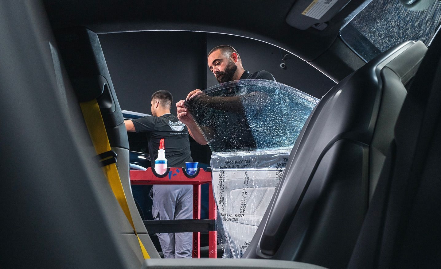 Close-up of technician lifting corner of window tint film during removal process.