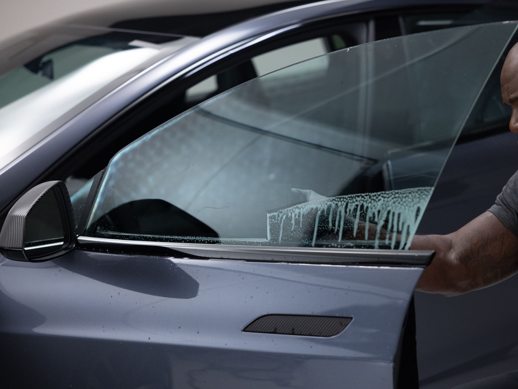 A man is cleaning a car window with a cloth