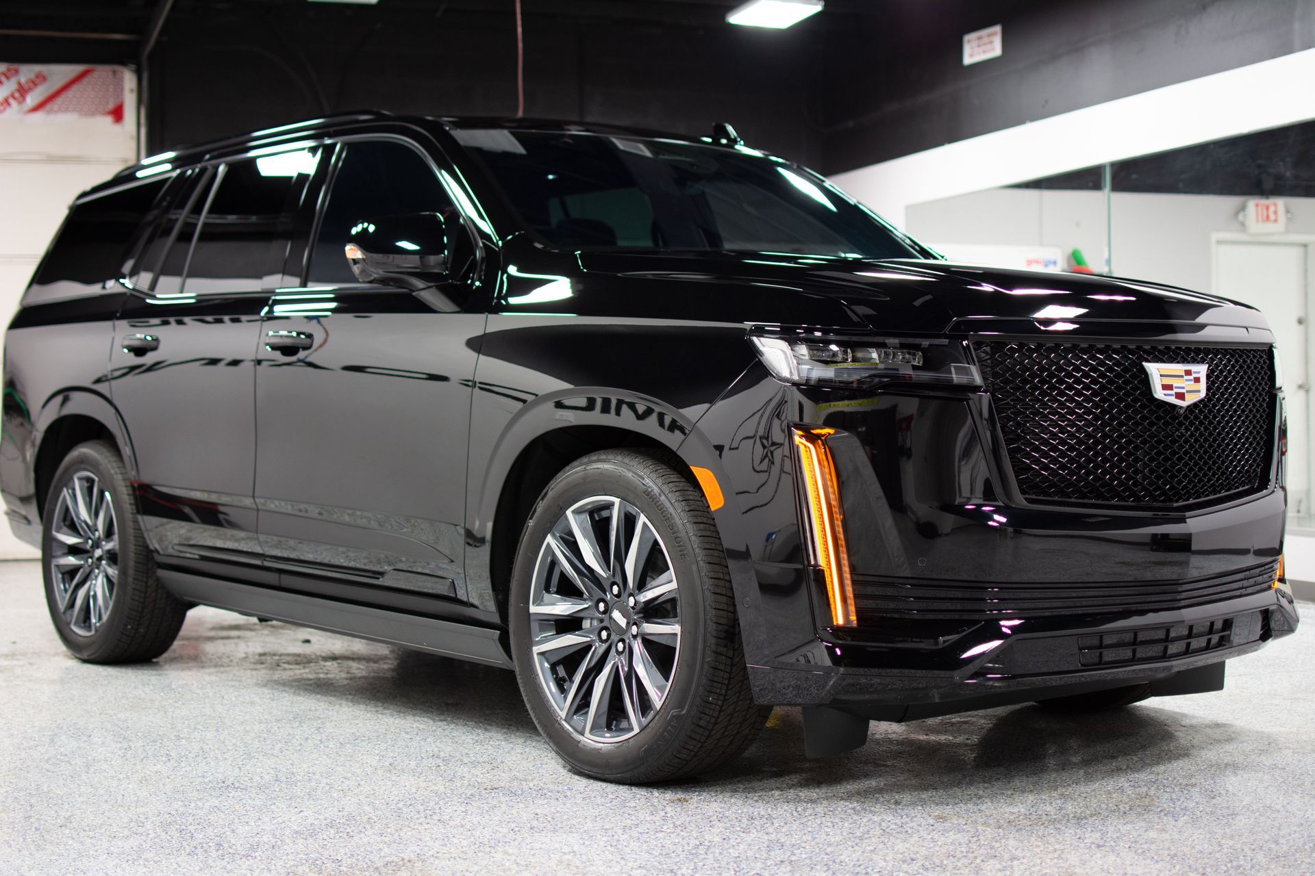 A black cadillac escalade is parked in a garage after a ceramic coating application.