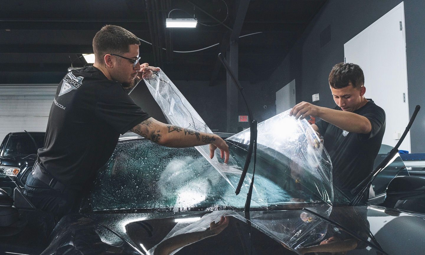 Expert applying high-quality window tint in a clean automotive workshop.