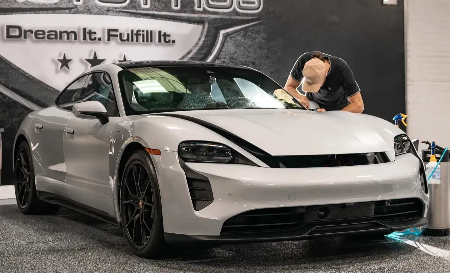 Technician carefully applying ceramic coating to a white luxury sports car to enhance paint protection and shine
