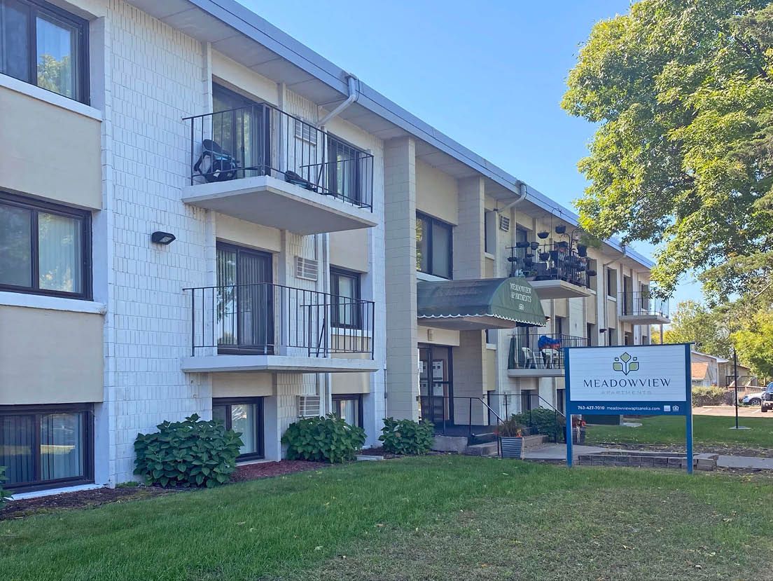 A large white apartment building with a sign in front of it.