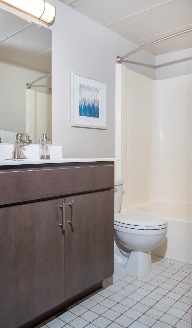 A bathroom with a toilet , sink , mirror and bathtub.