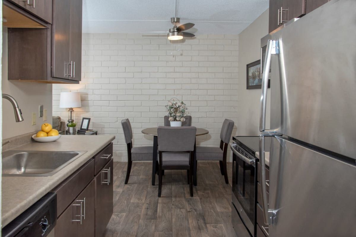 A kitchen with stainless steel appliances and a dining room with a table and chairs.