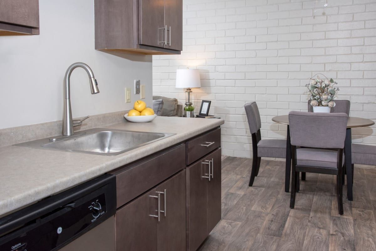 A kitchen with a sink , dishwasher , dining table and chairs.
